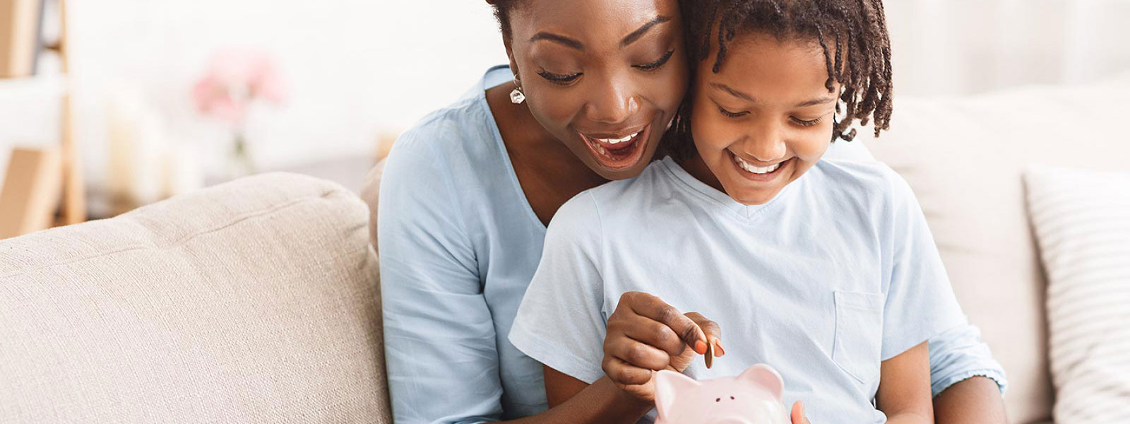 Mother and daughter putting money in piggy Bank